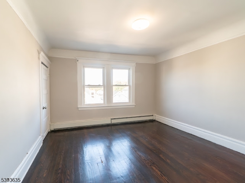134 Maple Avenue Irvington, NJ 07111 - Photo 21 of 29 an empty room with wooden floor and windows