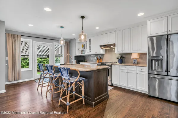 a kitchen with stainless steel appliances granite countertop a stove a refrigerator a sink a dining table and chairs with wooden floor