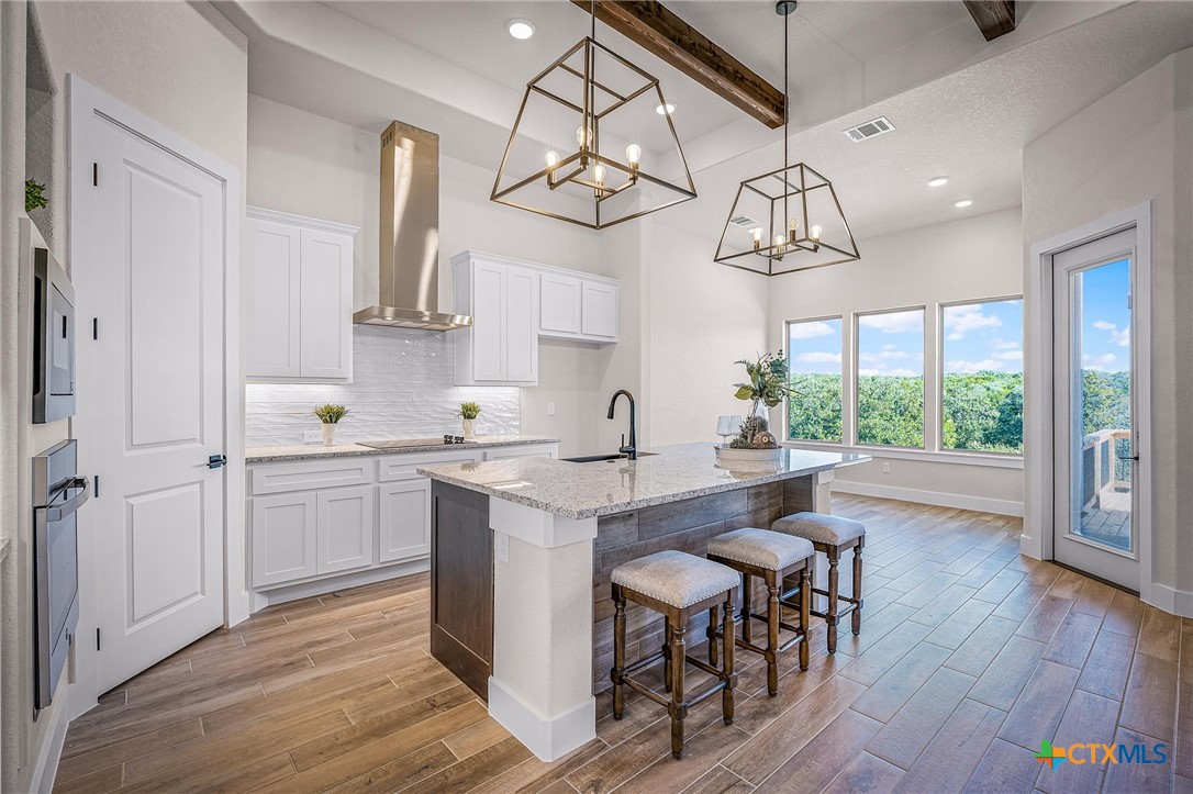319 Serenity Pass Spring Branch, TX 78070 - Photo 20 of 26 a kitchen with kitchen island granite countertop a table chairs in it and wooden floors