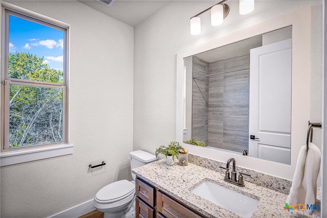 319 Serenity Pass Spring Branch, TX 78070 - Photo 8 of 26 a bathroom with a granite countertop sink a toilet a mirror and shower