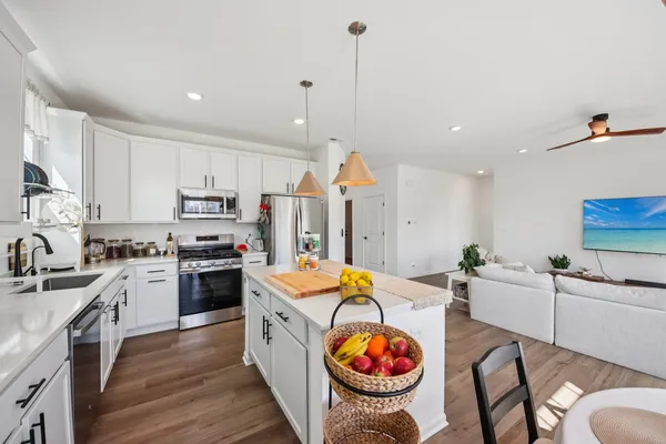 a kitchen with stainless steel appliances kitchen island granite countertop a stove a sink a refrigerator and white cabinets