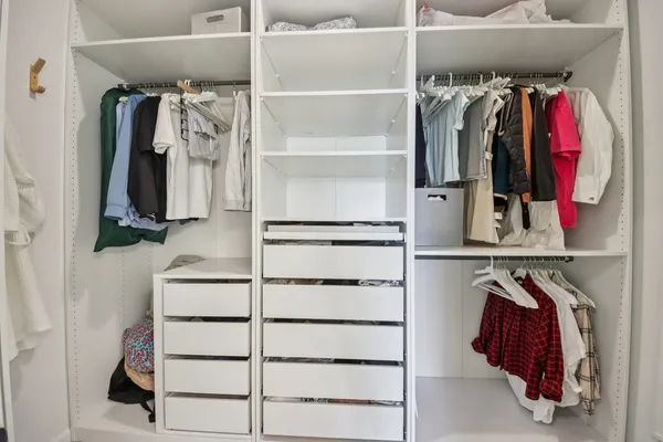 a view of walk in closet with clothes and shoes