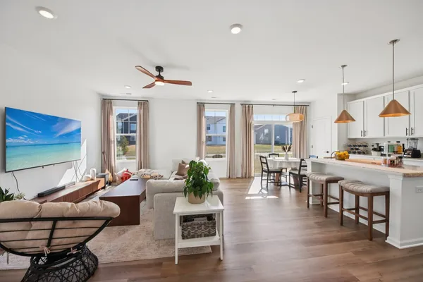 a living room with furniture kitchen view and large windows
