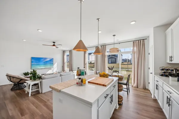 a open kitchen with stainless steel appliances granite countertop a stove a sink dishwasher a dining table and chairs with wooden floor