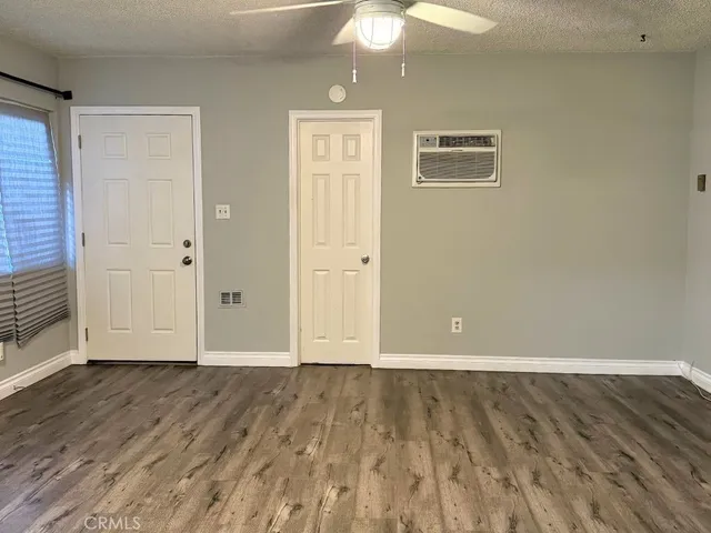 an empty room with wooden floor fan and windows