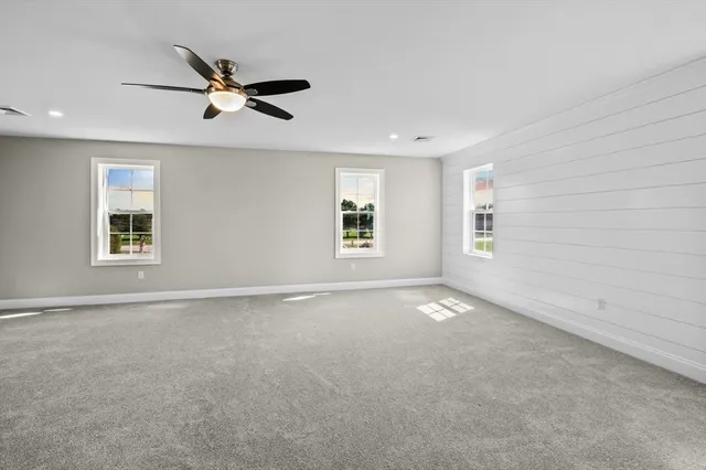 an empty room with a window and a ceiling fan