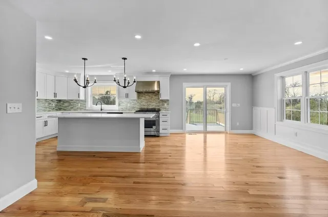 a large kitchen with stainless steel appliances a large counter top a stove and a wooden floors