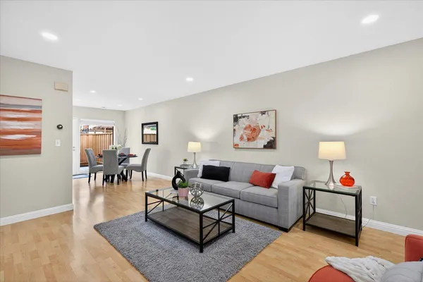 a living room with furniture and a dining table with wooden floor