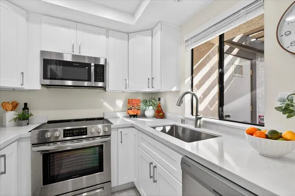 a kitchen with stainless steel appliances granite countertop a sink a stove a microwave and wooden cabinets