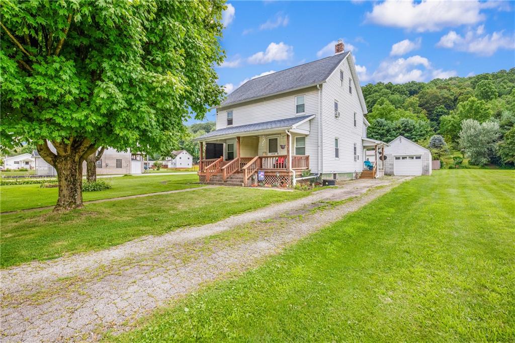 a view of a house with a big yard potted plants and large tree