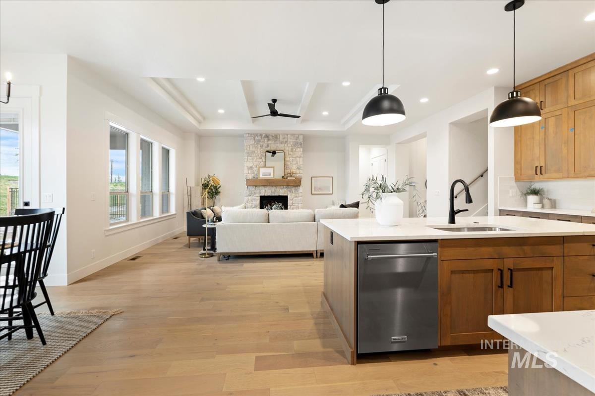 232 South Fusion Avenue Kuna, ID 83634 - Photo 23 of 30 Kitchen with dishwasher, decorative light fixtures, light wood-type flooring, a ceiling fan, and a stone fireplace