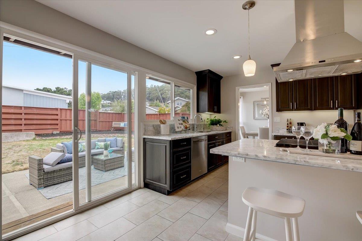 1209 Ridgewood Drive Millbrae, CA 94030 - Photo 17 of 59 a kitchen with stainless steel appliances kitchen island granite countertop a refrigerator a sink dishwasher a stove and a dining table with garden view