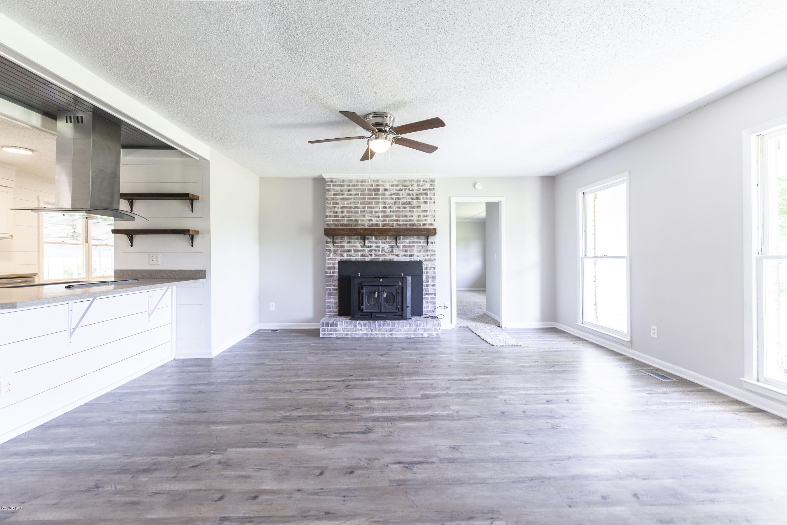 246 Allred Road Byron, GA 31008 - Photo 12 of 53 an empty room with wooden floor a kitchen view and a fireplace
