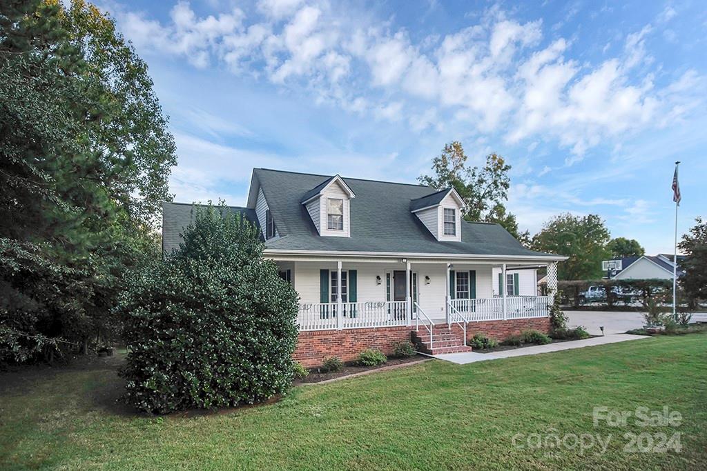 a view of a house with a big yard potted plants and large tree