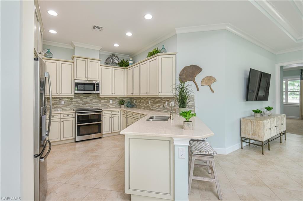 5764 Elbow Avenue Naples, FL 34113 - Photo 9 of 48 a kitchen with kitchen island white cabinets and stainless steel appliances