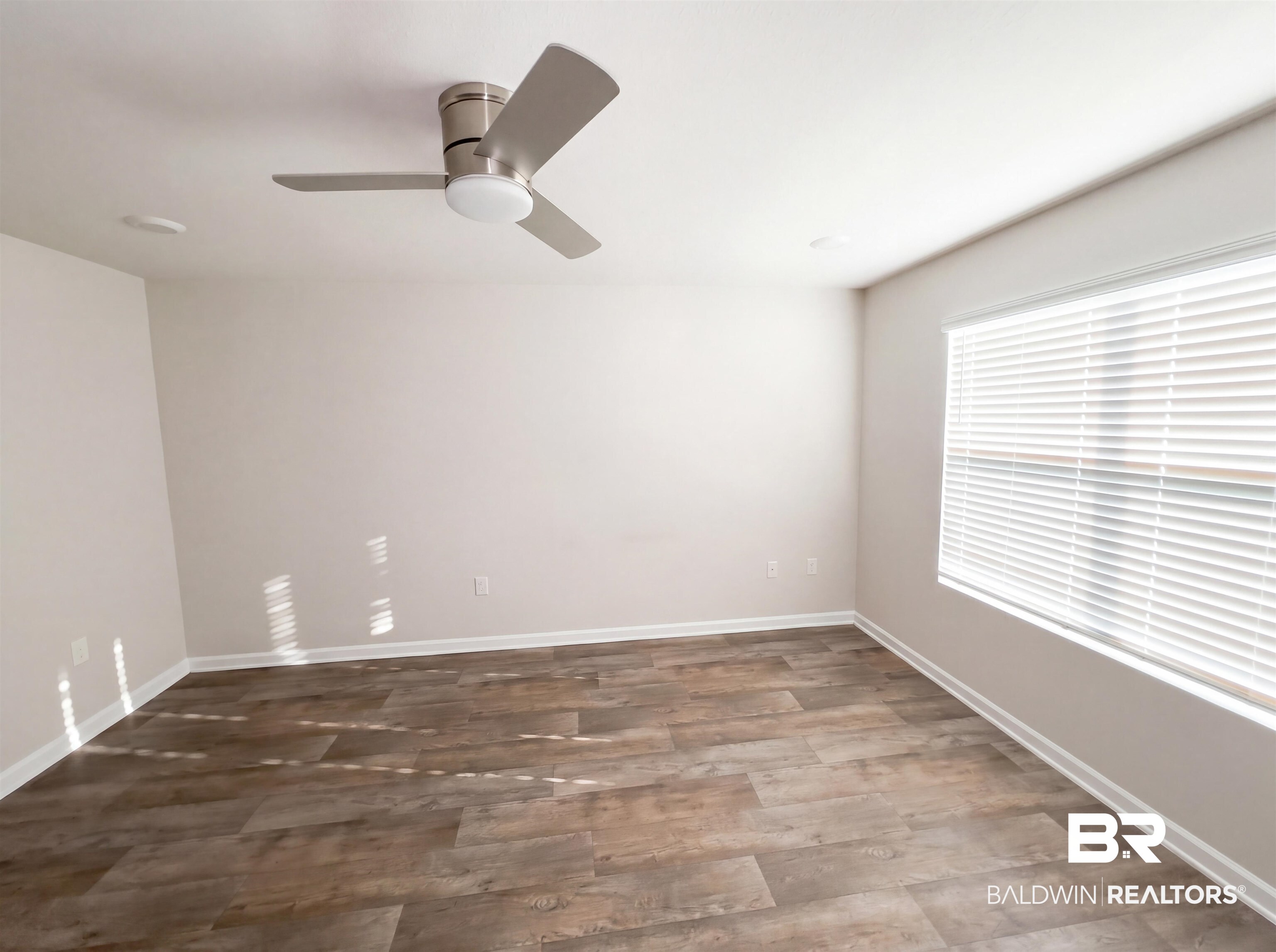 7453 Brompton Drive Foley, AL 36535 - Photo 11 of 15 Spacious room featuring wood-finish flooring, neutral-toned walls, and a contemporary ceiling fan with integrated lighting