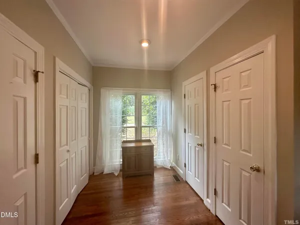 a view of a hallway with wooden floor and a bathroom
