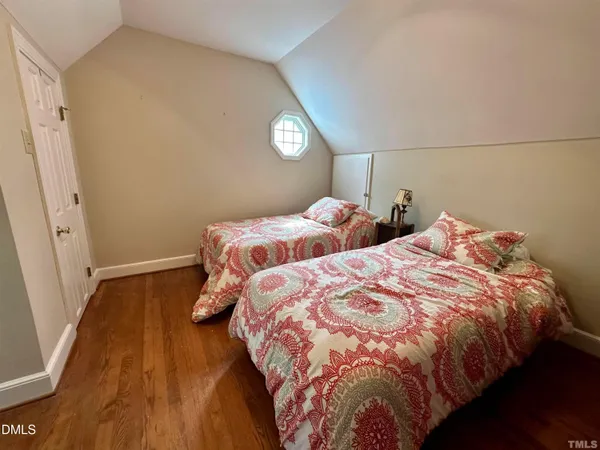a bedroom with two beds and wooden floor