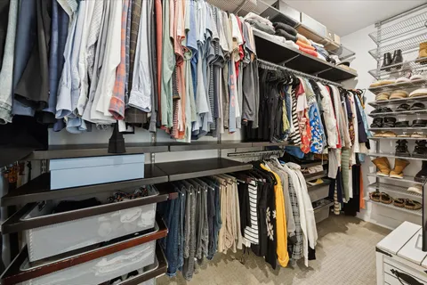 a view of walk in closet with clothes and shoes