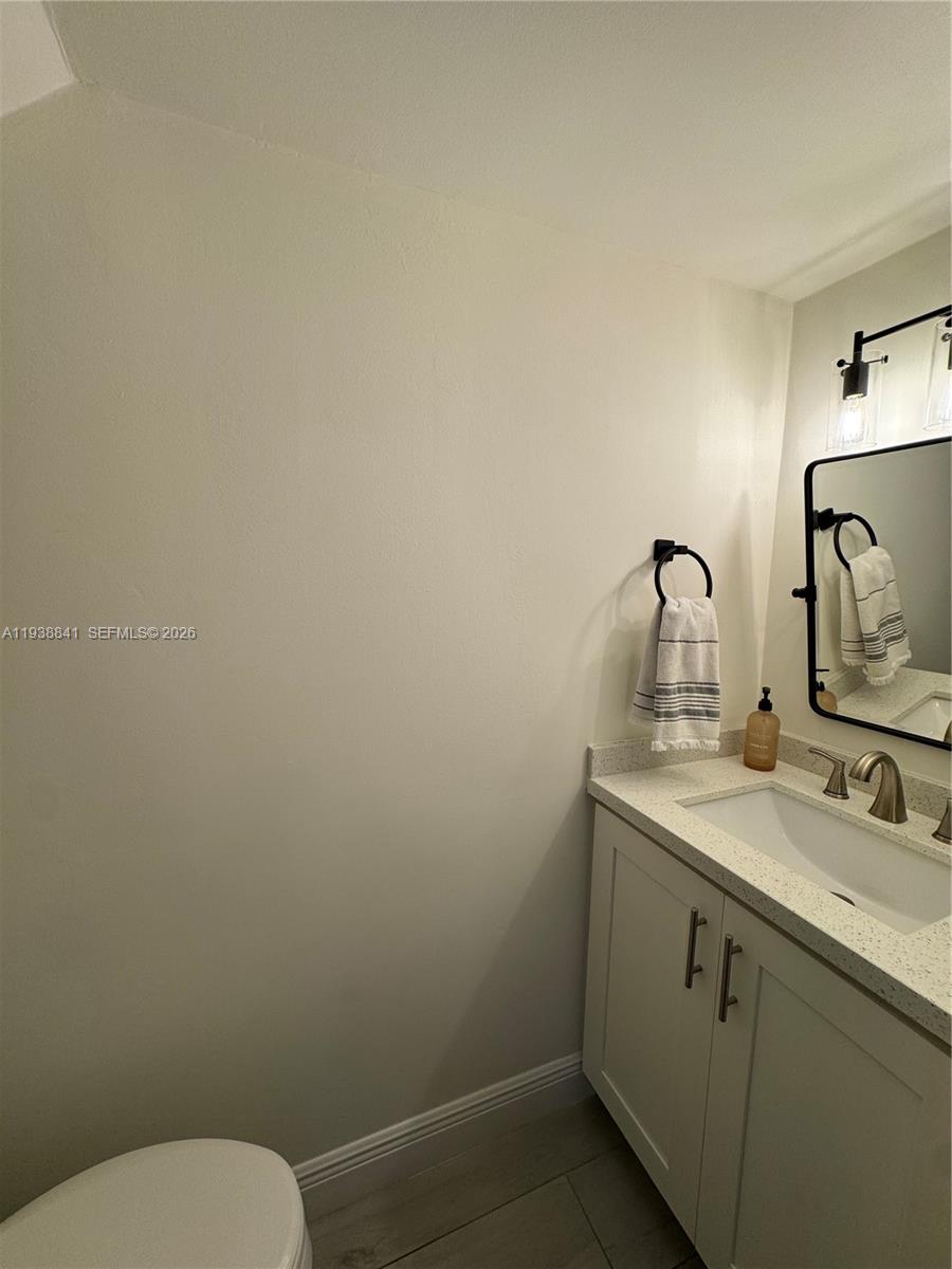 10069 Southwest 77th Court Miami, FL 33156 - Photo 13 of 16 a bathroom with a toilet sink vanity and mirror
