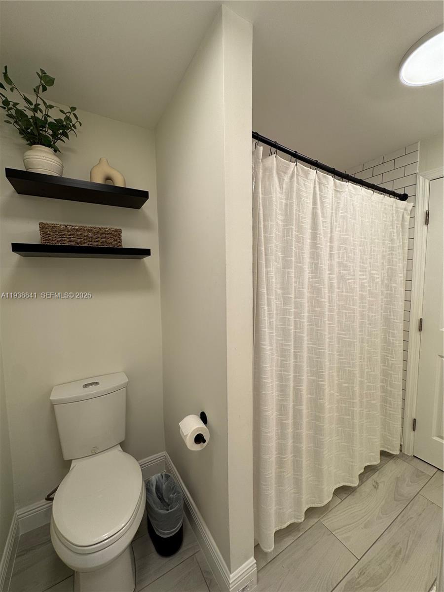 10069 Southwest 77th Court Miami, FL 33156 - Photo 6 of 16 a bathroom with a toilet and a shower curtain