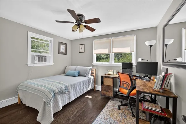 a bedroom with a bed a desk and chair with a large windows