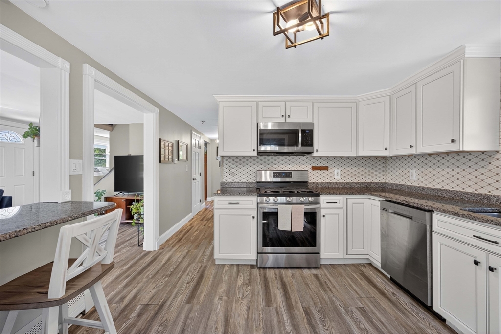 181 Head Of The Bay Road Bourne, MA 02532 - Photo 6 of 34 a kitchen with stainless steel appliances granite countertop a stove top oven a sink dishwasher and a refrigerator with wooden floor