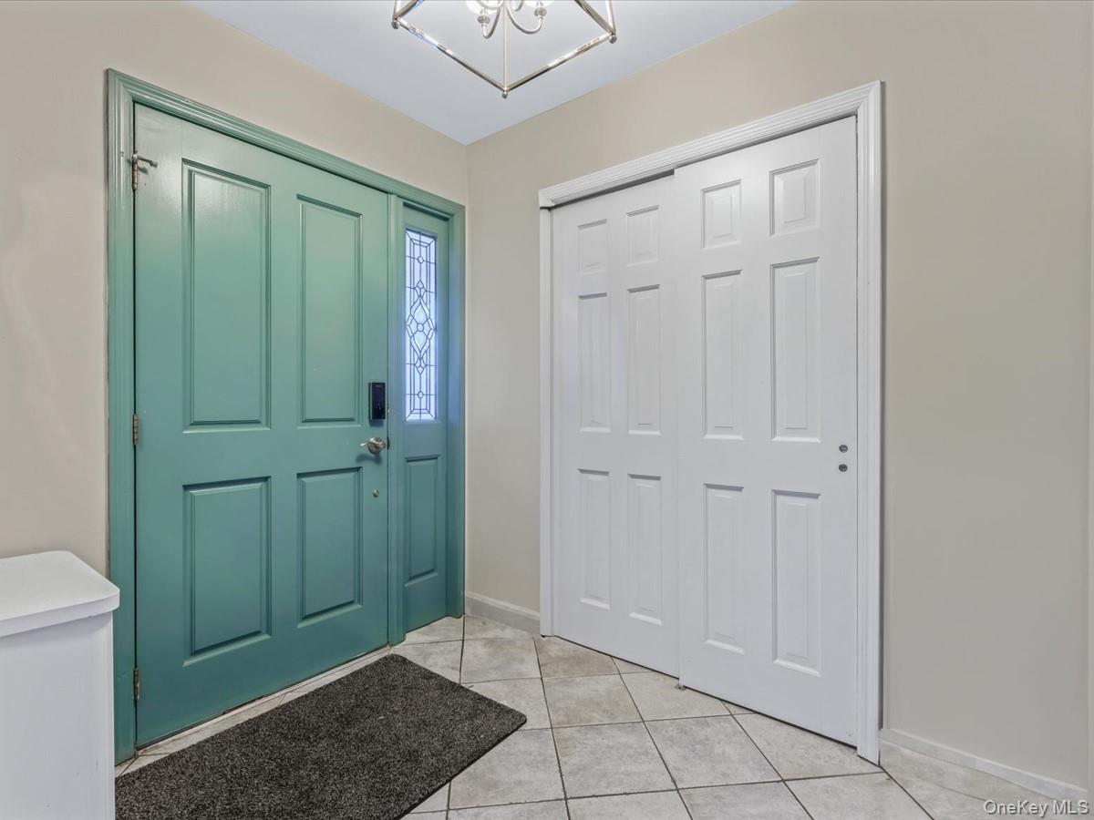 217-32 Corbett Road Queens, NY 11361 - Photo 3 of 25 Entrance foyer featuring light tile patterned floors and a chandelier