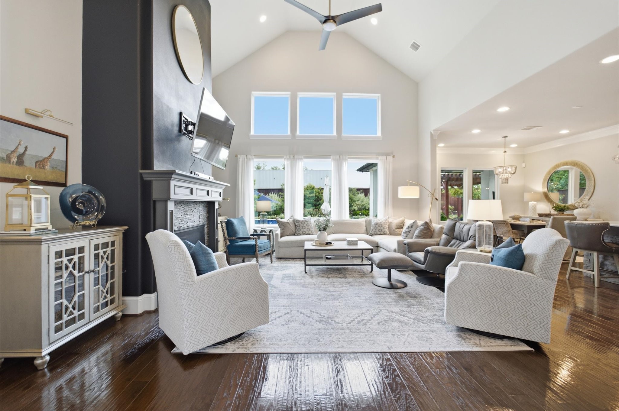 23722 Thortons Park Lane Spring, TX 77389 - Photo 48 of 48 This spacious living area features high ceilings and abundant natural light from large windows. It includes a cozy fireplace, elegant seating, and an open floor plan connecting to a dining area, ideal for modern living and entertaining.