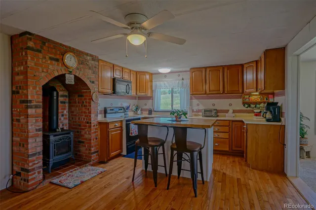 a kitchen with stainless steel appliances granite countertop a stove top oven a refrigerator a sink and dishwasher with wooden floor