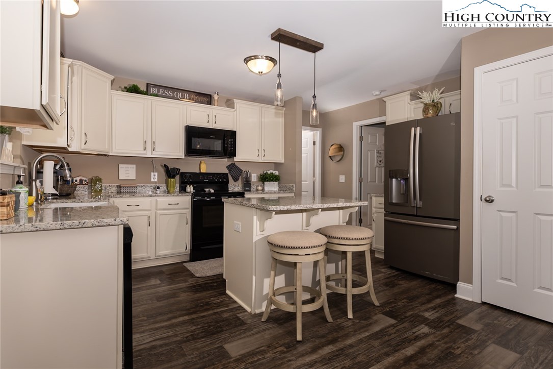 351 Colony Lane Purlear, NC 28665 - Photo 23 of 39 a kitchen with a refrigerator a microwave oven a sink a dining table and chairs with wooden floor