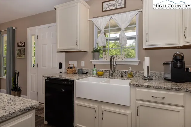 a kitchen with granite countertop a sink stainless steel appliances white cabinets and a granite counter tops
