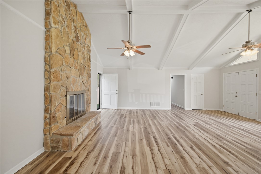 902 Cherokee Road Pelzer, SC 29669 - Photo 6 of 38 A spacious common area boasts a floor-to-ceiling stone fireplace and vaulted ceilings with exposed beams.