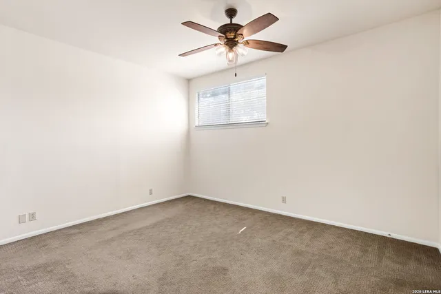 an empty room with a chandelier fan and windows