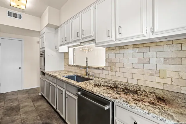 a kitchen with granite countertop a stove sink and cabinets