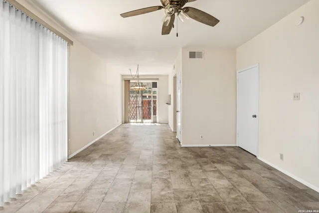 a view of empty room with a window and a ceiling fan
