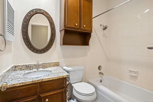 a bathroom with a granite countertop toilet a sink and a mirror