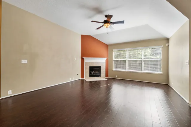 a view of an empty room with wooden floor fireplace and a window