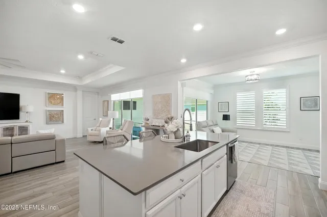 a kitchen with granite countertop a stove a sink dishwasher and white cabinets with wooden floor