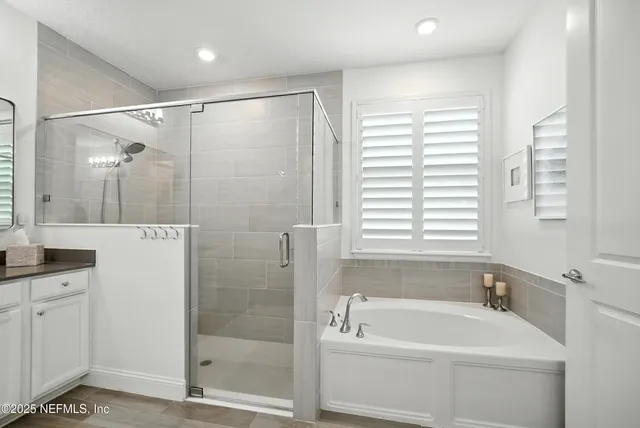 a bathroom with a tub sink double vanity granite tub shower and mirror