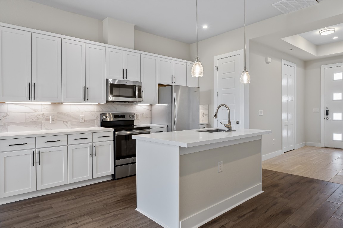 a kitchen with kitchen island a sink stainless steel appliances and cabinets