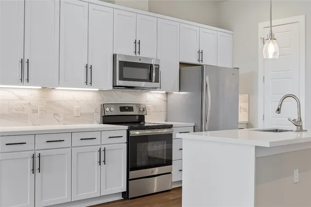 a kitchen with a sink stainless steel appliances and white cabinets