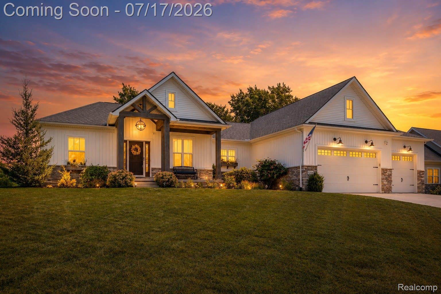 12349 Sugar Maple Drive Fenton, MI 48430 - Photo 1 of 67 Modern farmhouse exterior featuring board and batten siding, stone accents, a covered front porch with substantial wood columns, a multi-car garage with barn-style lighting, and a sloped front lawn