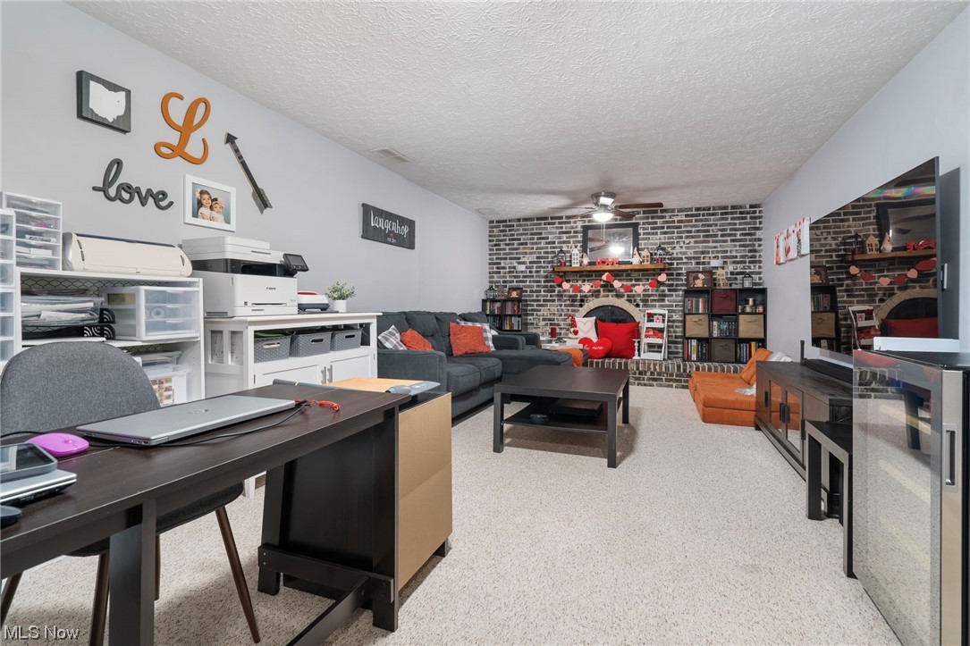 801 Netherwood Avenue Northwest Canton, OH 44708 - Photo 25 of 44 Family room featuring a brick fireplace, brick wall, a textured ceiling, and ceiling fan