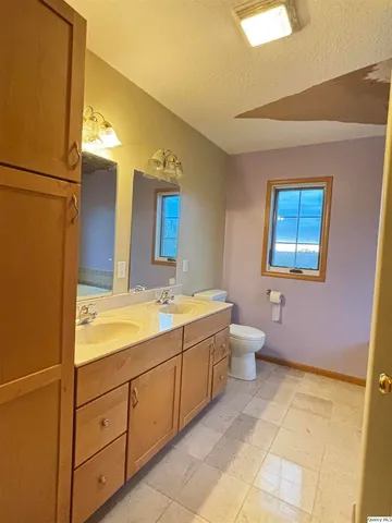 a spacious bathroom with a double vanity sink a mirror and a toilet