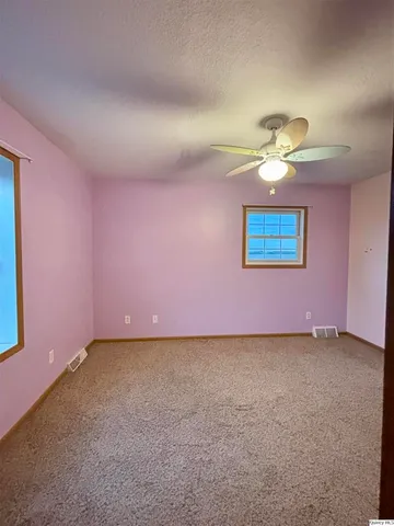 an empty room with windows and fan