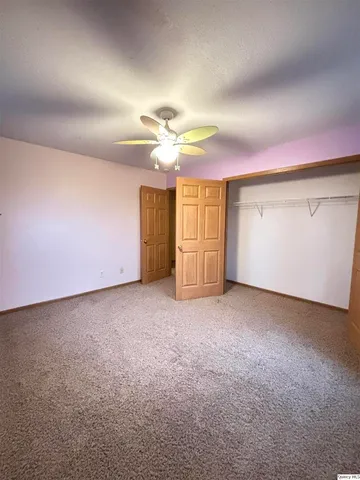 an empty room with windows and fan