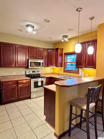 a kitchen with kitchen island granite countertop wooden cabinets and stainless steel appliances