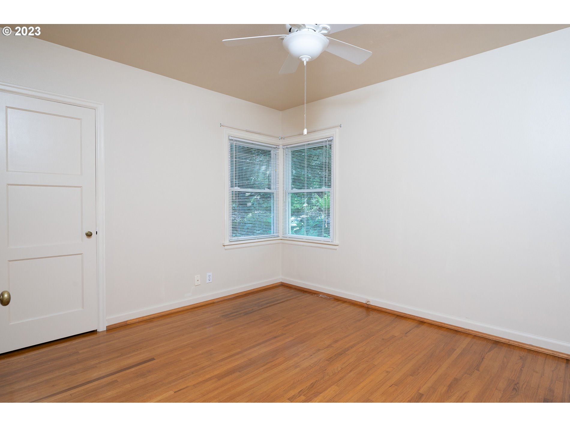 8201 Southwest 41st Avenue Portland, OR 97219 - Photo 13 of 23 an empty room with wooden floor chandelier fan and windows