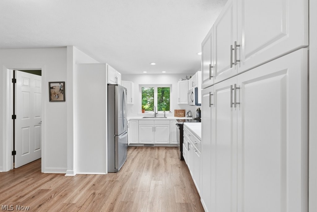 2323 Call Road Stow, OH 44224 - Photo 11 of 42 Contemporary kitchen featuring white shaker cabinetry, stainless steel appliances, wood-finish flooring, recessed lighting, and a window with exterior greenery